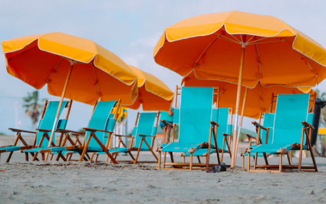 Yellow umbrellas and blue folding chairs on a beach.